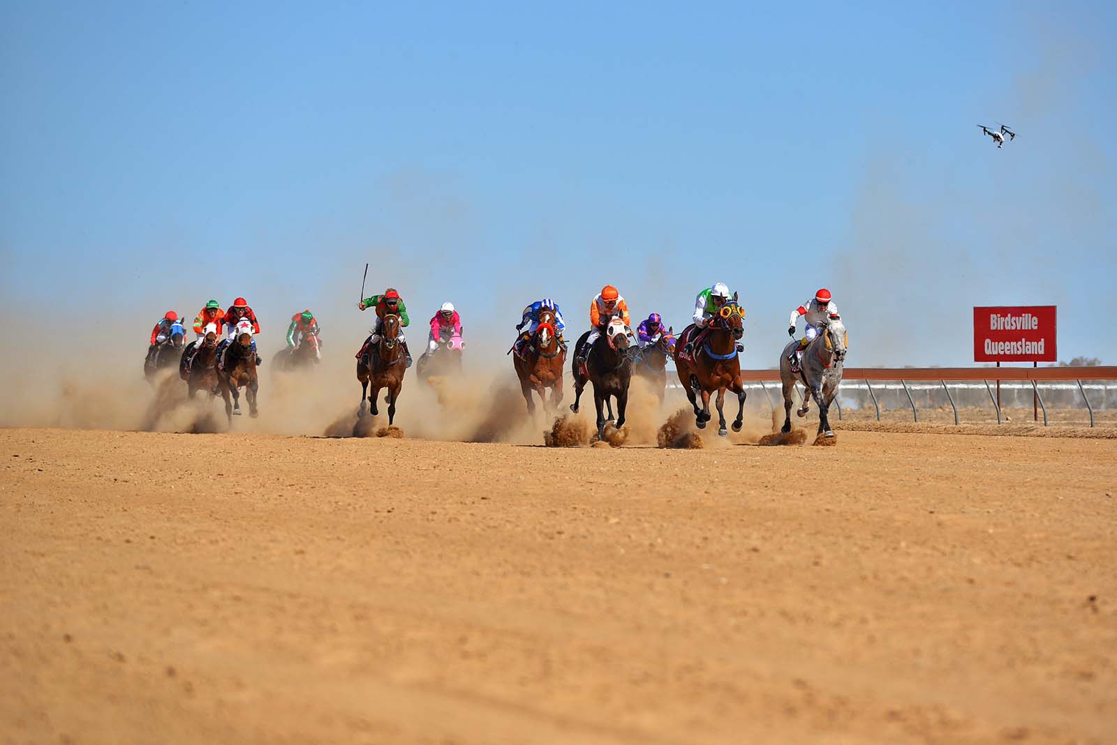 Horses race down the dirt track at the Birdsville Races | A bird's eye view of Birdsville