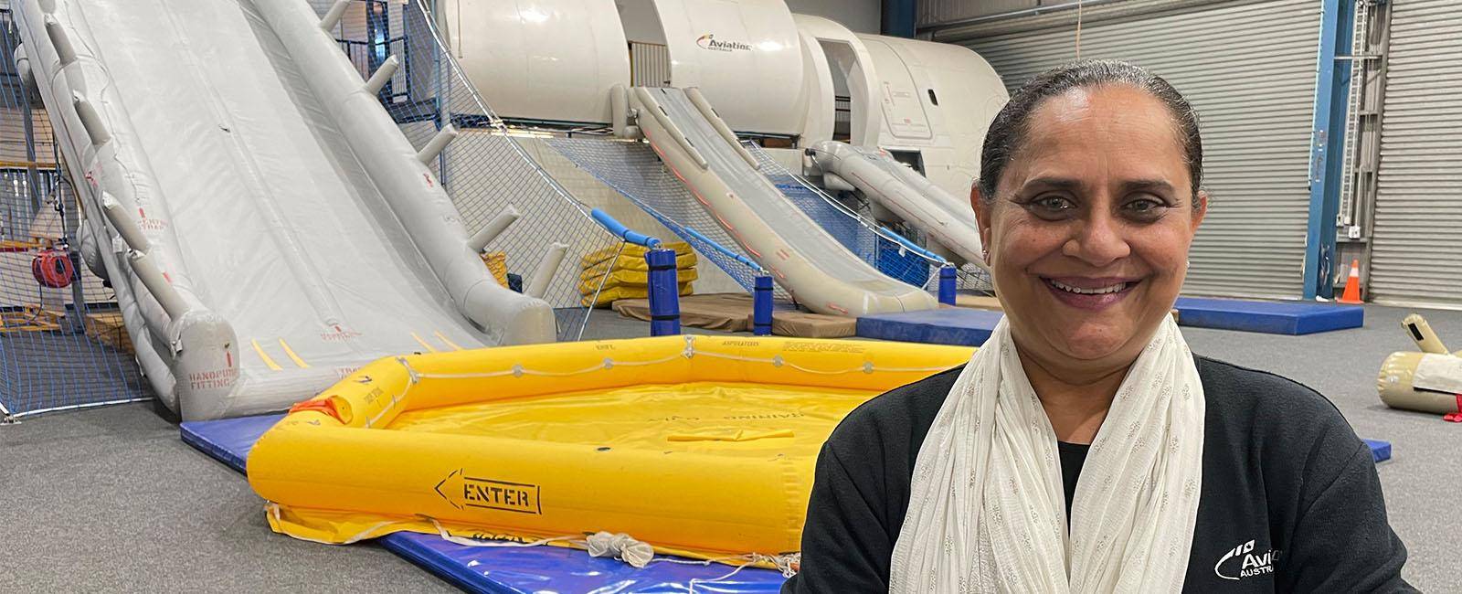 Harsha Patel standing in front of aviation training equipment - rafts and evacuation slides.  