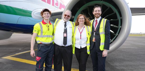 Family of four in yellow high-vis in front of a jet engine